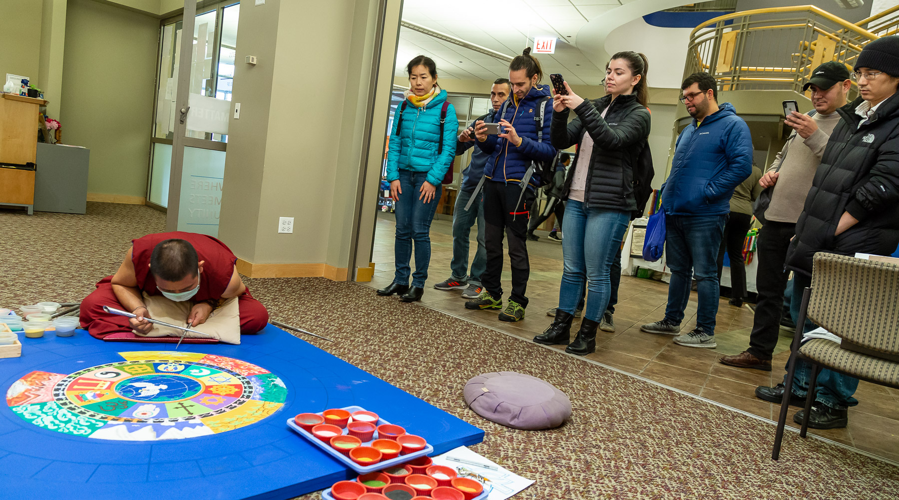 Onlookers watch a Buddhist monk create a sand mandala, Wednesday, Oct. 31, in the Lincoln Park Student Center. (DePaul University/Jeff Carrion)